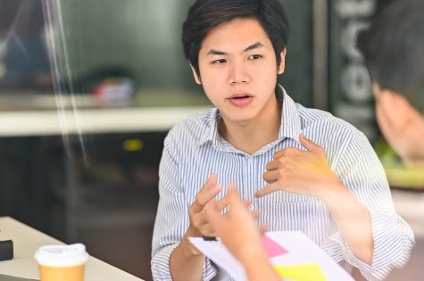 Close up young male talking to colleagues consulting in modern office.